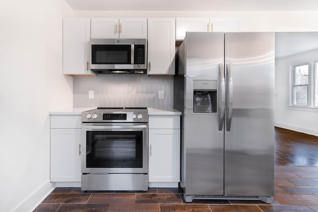 kitchen with wood finish floors, stainless steel appliances, tasteful backsplash, light countertops, and white cabinets