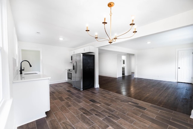 kitchen with decorative light fixtures, stainless steel appliances, light countertops, white cabinetry, and a sink