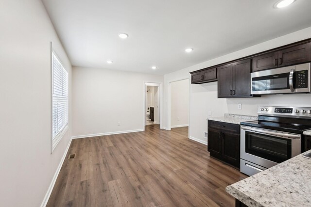 kitchen featuring light stone counters, dark brown cabinetry, visible vents, appliances with stainless steel finishes, and dark wood finished floors