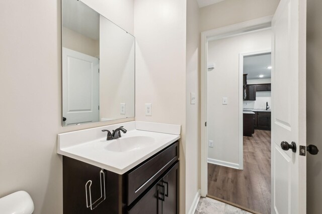 bathroom with wood finished floors, vanity, and baseboards