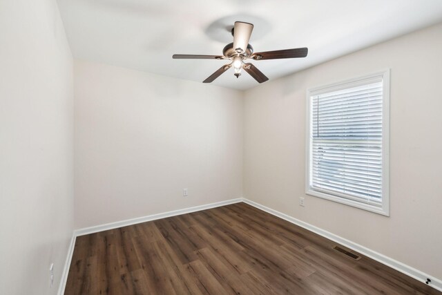 empty room featuring a ceiling fan, dark wood-style flooring, visible vents, and baseboards