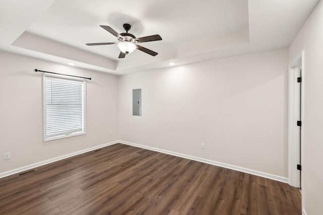 empty room featuring a tray ceiling, visible vents, and baseboards