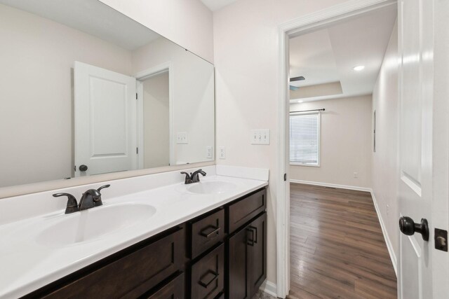 full bathroom with double vanity, baseboards, a sink, and wood finished floors