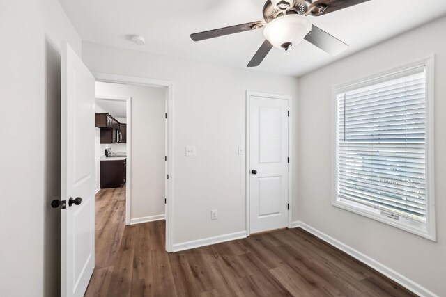 unfurnished bedroom featuring dark wood-style floors, a ceiling fan, and baseboards