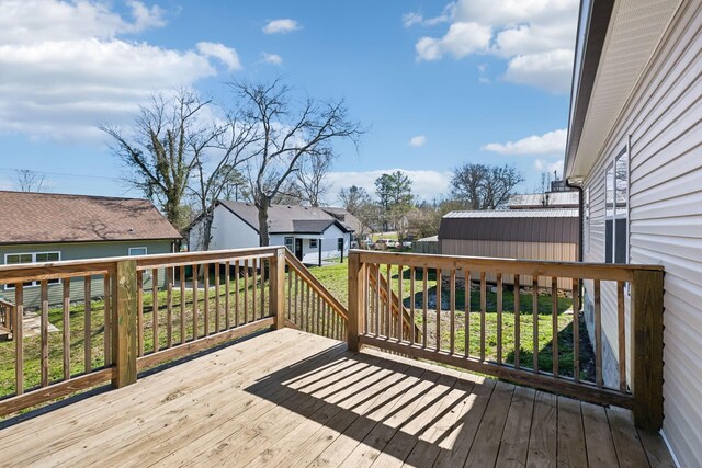 deck with a residential view, an outdoor structure, a storage shed, and a lawn