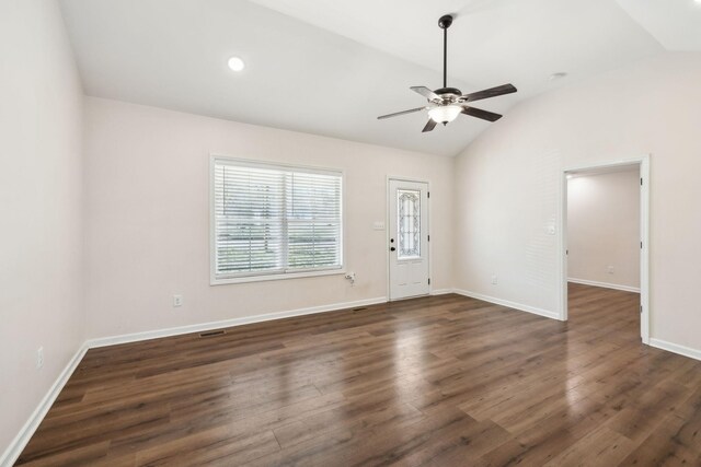 empty room featuring lofted ceiling, baseboards, dark wood finished floors, and a ceiling fan