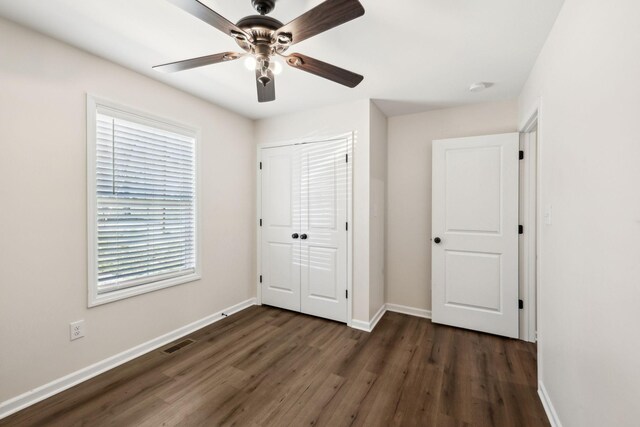 unfurnished bedroom featuring a closet, visible vents, dark wood finished floors, and baseboards