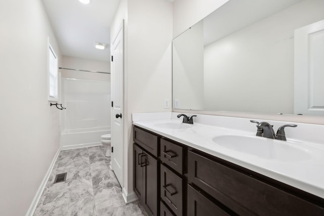 bathroom with toilet, double vanity, a sink, and shower / bathing tub combination