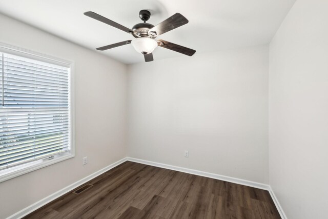 spare room featuring baseboards, visible vents, ceiling fan, and dark wood-style flooring