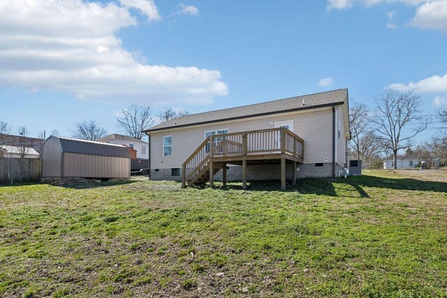 back of house with a deck, an outdoor structure, crawl space, a lawn, and a shed