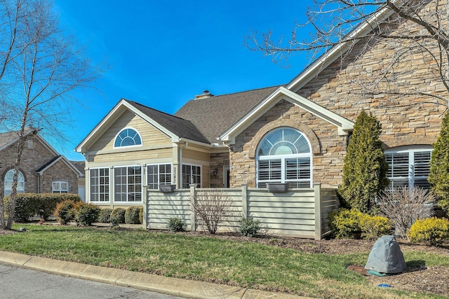 view of front of house with stone siding, a front lawn, and a chimney