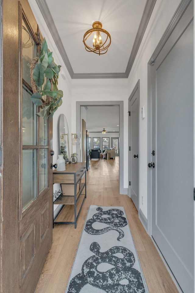 entryway with light wood finished floors, baseboards, crown molding, and an inviting chandelier