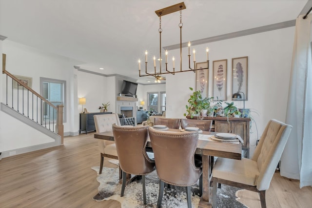 dining space with a fireplace, light wood-style flooring, and crown molding