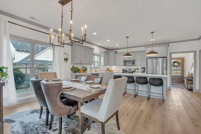 dining room featuring light wood finished floors, plenty of natural light, visible vents, and ornamental molding