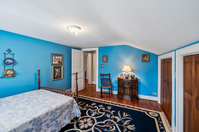 bedroom with multiple closets, baseboards, dark wood-type flooring, and lofted ceiling