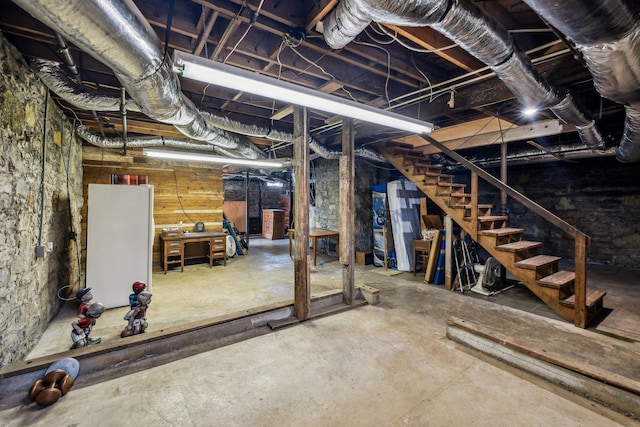 unfinished basement featuring freestanding refrigerator