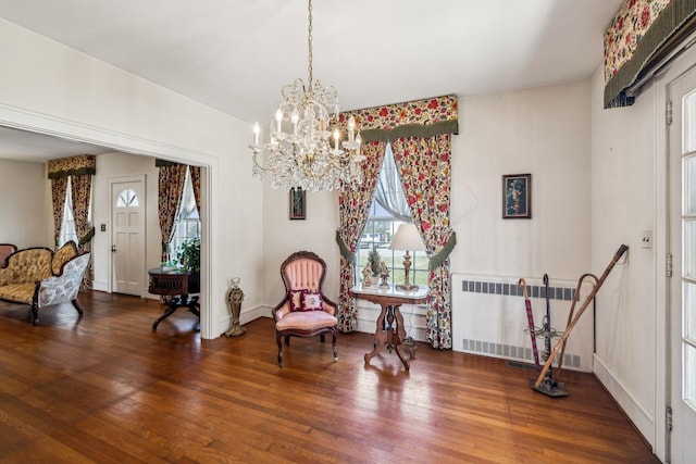 living area featuring baseboards, radiator heating unit, wood finished floors, and an inviting chandelier