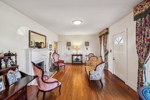 sitting room featuring dark wood finished floors, a fireplace, and baseboards