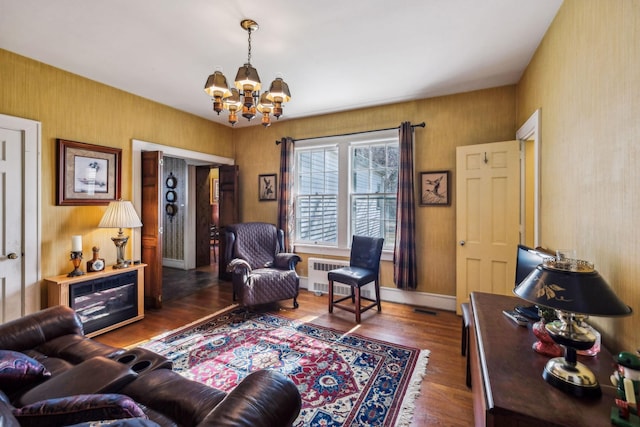 living room featuring a chandelier, radiator, baseboards, and wood finished floors