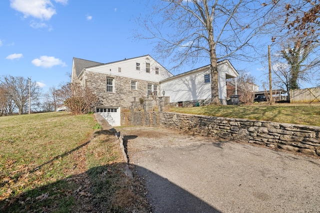 exterior space with stone siding, a front yard, concrete driveway, and an attached garage