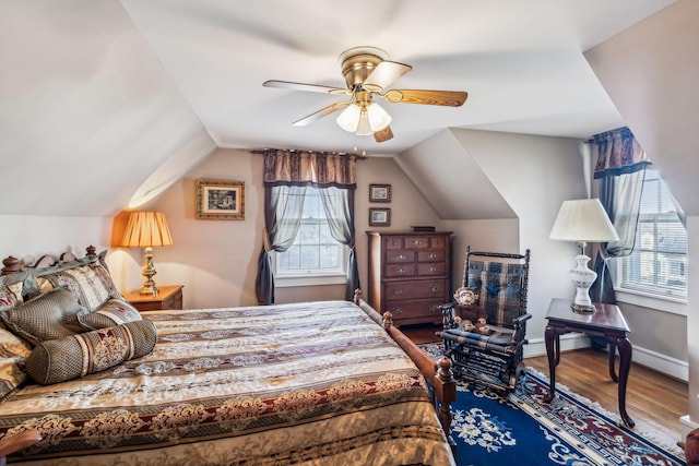 bedroom with lofted ceiling, multiple windows, baseboards, and wood finished floors