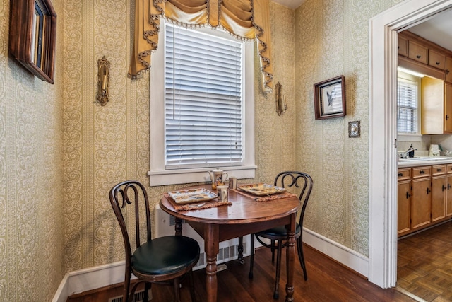 dining space featuring parquet floors, wallpapered walls, and baseboards