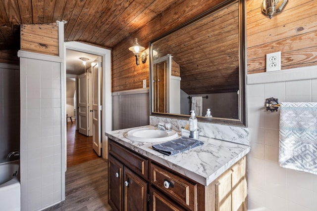 bathroom featuring lofted ceiling, wooden ceiling, wood finished floors, a washtub, and vanity