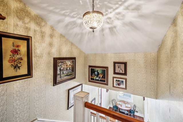 stairs with lofted ceiling and an inviting chandelier