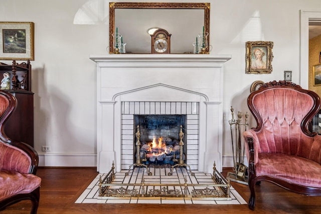 sitting room featuring a brick fireplace, baseboards, and wood finished floors