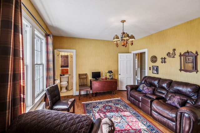 living area with an inviting chandelier, wallpapered walls, and wood finished floors