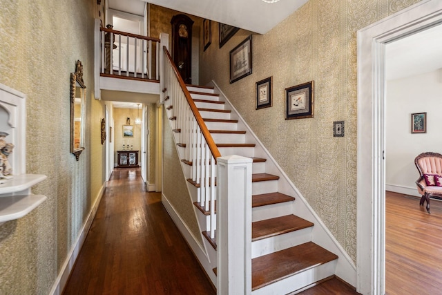 stairway with wallpapered walls, baseboards, and wood finished floors