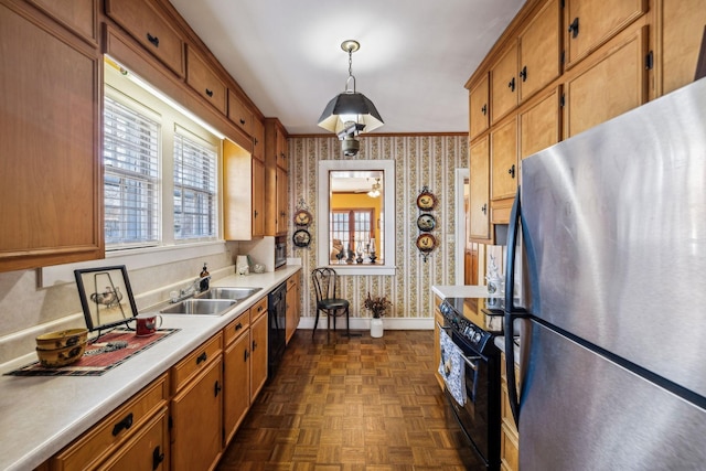 kitchen featuring black appliances, hanging light fixtures, light countertops, and wallpapered walls