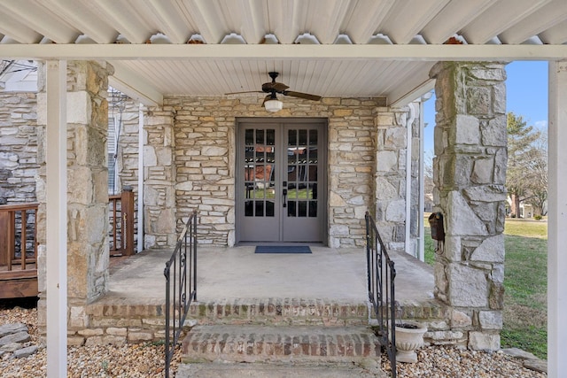 entrance to property with stone siding, french doors, and ceiling fan