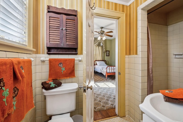 bathroom with toilet, ceiling fan, and tile walls