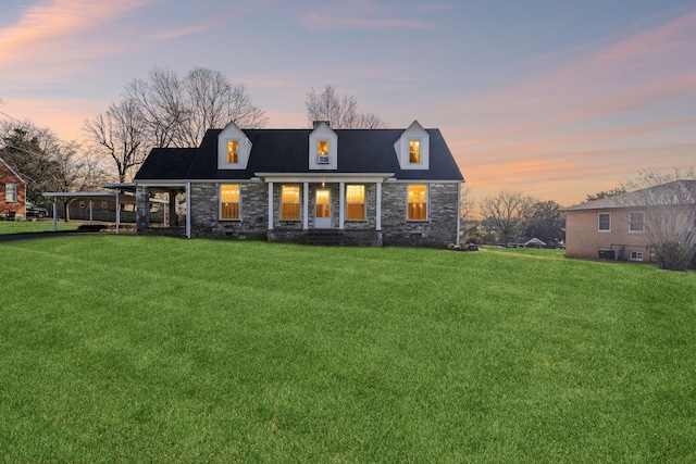 rear view of house featuring stone siding, central AC unit, and a lawn