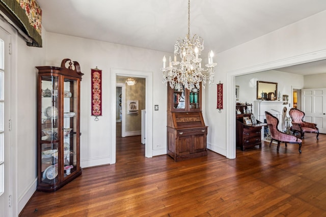 interior space with dark wood-style flooring, a notable chandelier, a fireplace, and baseboards