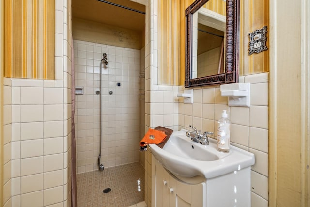 bathroom with wainscoting, tiled shower, tile walls, and vanity