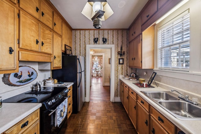 kitchen featuring brown cabinets, light countertops, electric range, a sink, and wallpapered walls