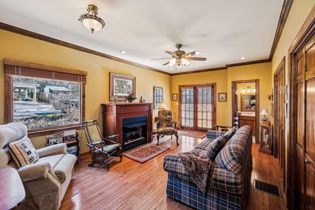 living room with french doors, a fireplace, visible vents, ornamental molding, and wood finished floors