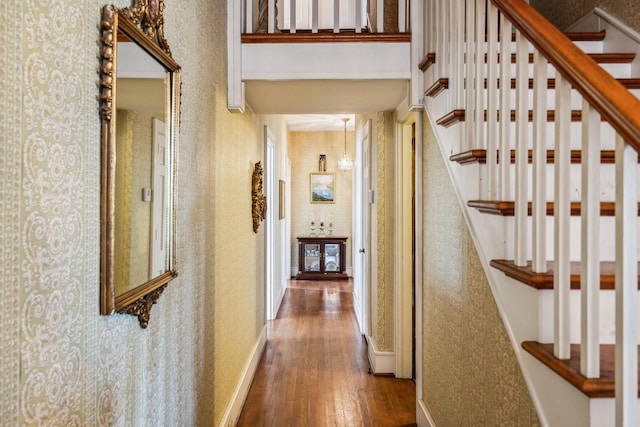 hallway featuring wallpapered walls, stairway, baseboards, and wood finished floors