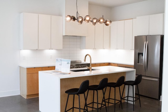 kitchen with white cabinets, a center island with sink, and stainless steel refrigerator with ice dispenser