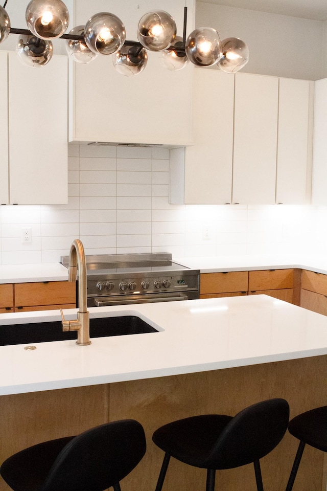 kitchen with tasteful backsplash, light countertops, white cabinetry, and a breakfast bar