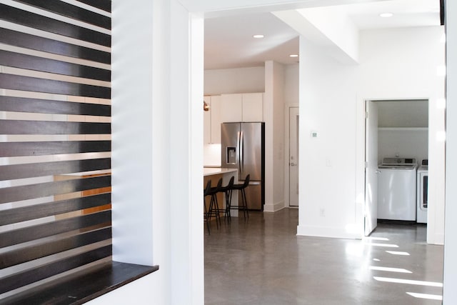 hall featuring baseboards, washer and clothes dryer, recessed lighting, and finished concrete floors