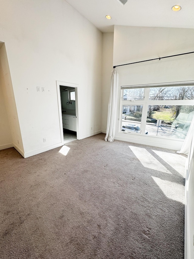 unfurnished living room featuring carpet floors, high vaulted ceiling, and baseboards