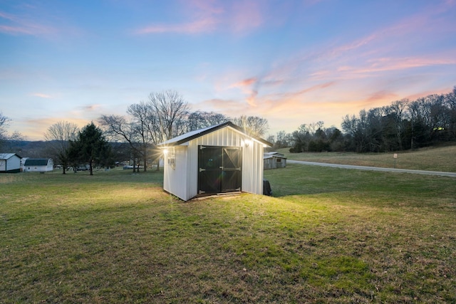 outdoor structure at dusk with a storage shed, an outbuilding, and a yard