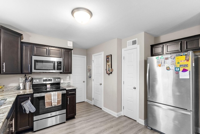 kitchen with appliances with stainless steel finishes, dark brown cabinetry, and light stone counters