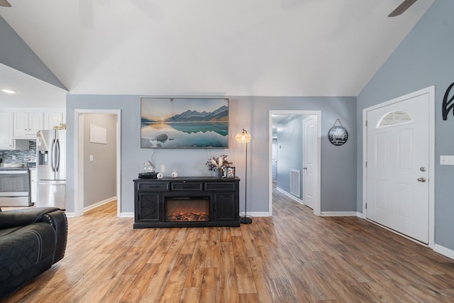 living area with lofted ceiling, light wood finished floors, and a glass covered fireplace