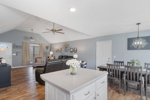 kitchen with lofted ceiling, wood finished floors, white cabinets, open floor plan, and a center island