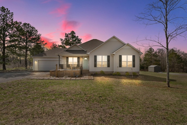 view of front of home featuring driveway, a storage shed, an attached garage, a porch, and a front yard