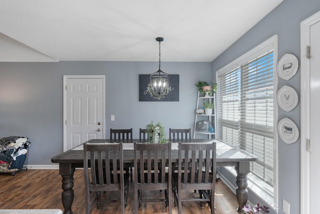 dining space featuring dark wood-style floors, a chandelier, and baseboards